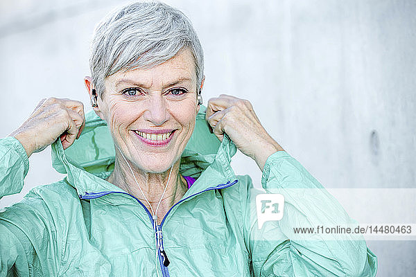 Porträt einer lächelnden  sportlichen  reifen Frau mit Ohrstöpseln