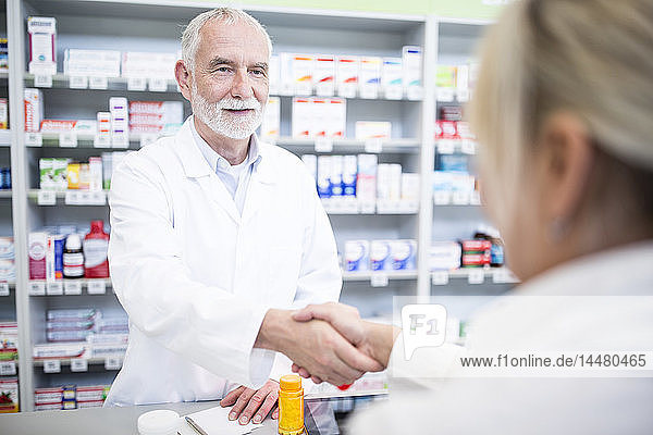 Pharmacist and customer shaking hands in pharmacy
