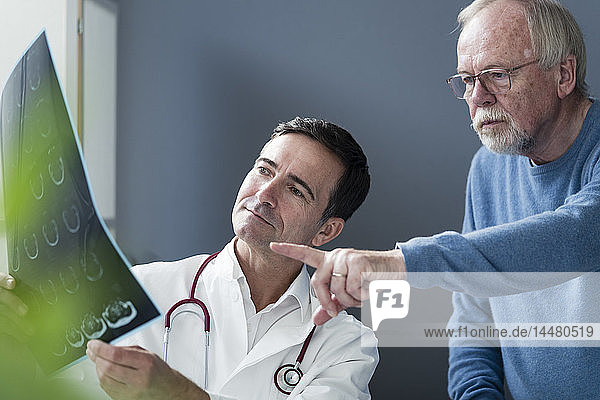 Arzt bespricht MRT-Bild mit älterem Patienten in medizinischer Praxis