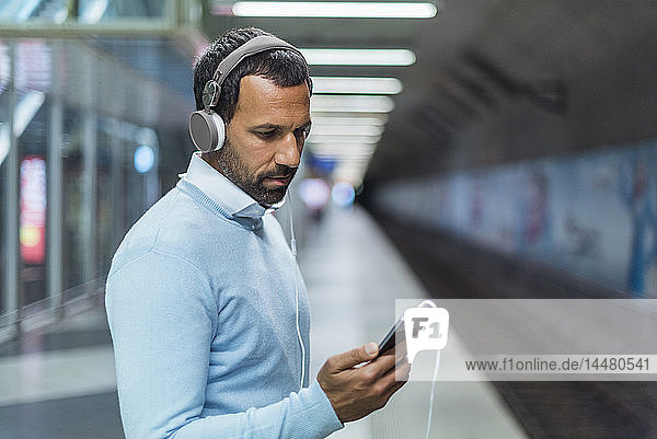 Geschäftsmann benutzt Smartphone an der U-Bahn-Station