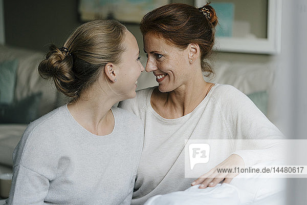 Happy mother with teenage girl face to face on couch at home
