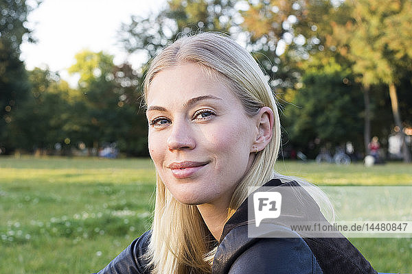 Porträt einer zufriedenen blonden Frau  die sich in einem Park entspannt