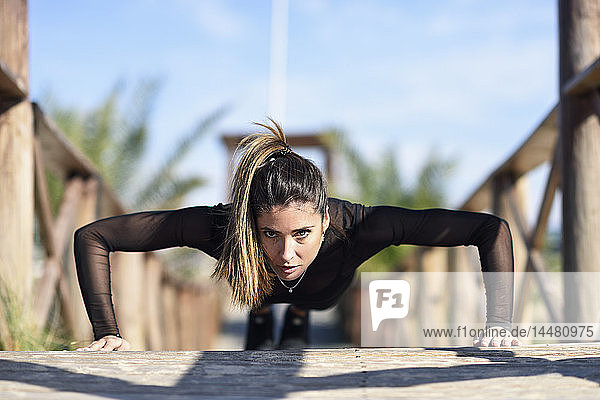 Sportliche Frau macht Liegestütze auf Holzbrücke