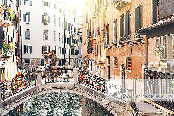 Italien  Venedig  junges Paar  das auf einer kleinen Brücke steht und sich ein Selfie