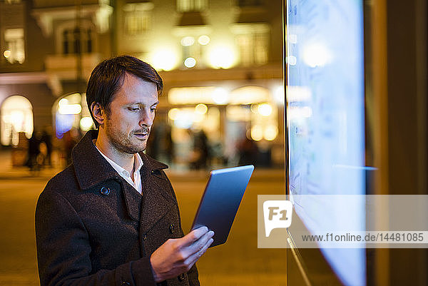 Businessman using digital tablet at night in the city