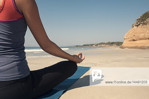 Nahaufnahme einer jungen Frau  die an einem Strand Yoga praktiziert