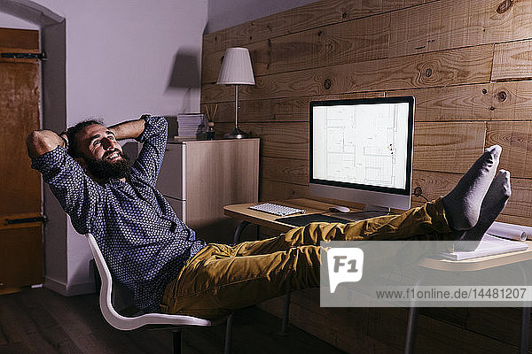Young happy architect after finishing a new project at home at night