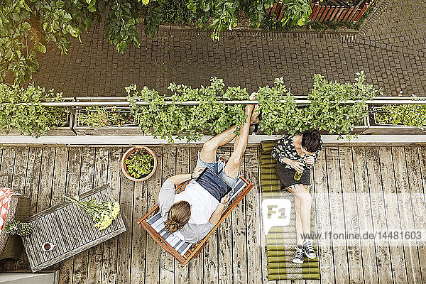 Young couple relaxing on their balcony in summer  man using tablet