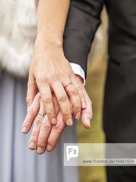 Nahaufnahme von Braut und Bräutigam beim Händchenhalten