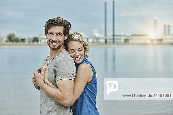 Glückliches junges Paar umarmt sich am Flussufer