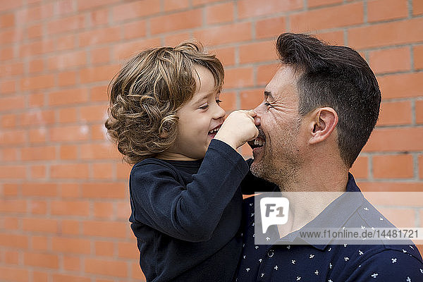 Playful father and son at brick wall