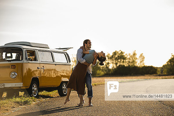 Glückliches Paar macht eine Autoreise mit einem Wohnmobil  lacht und umarmt sich unterwegs