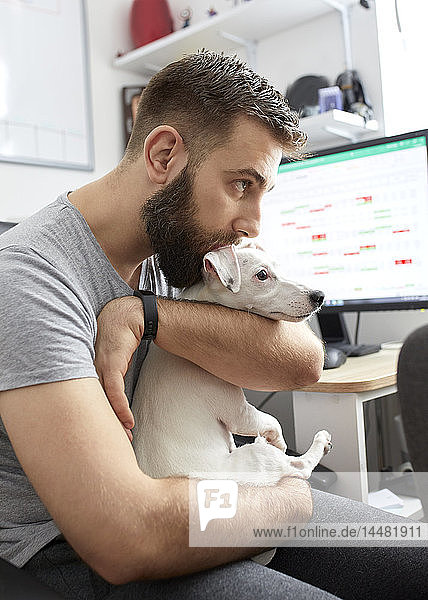 Mann kuschelt seinen Hund im Heimbüro
