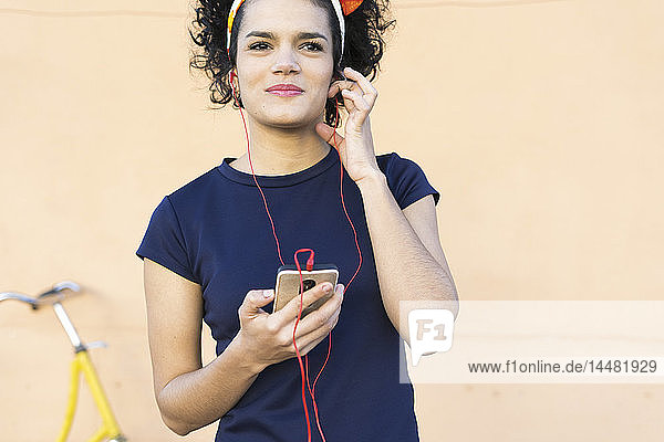 Lächelnde junge Frau mit Smartphone  die Musik hört