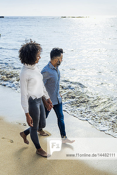 Spain  Barcelona  couple walking barefoot on the beach