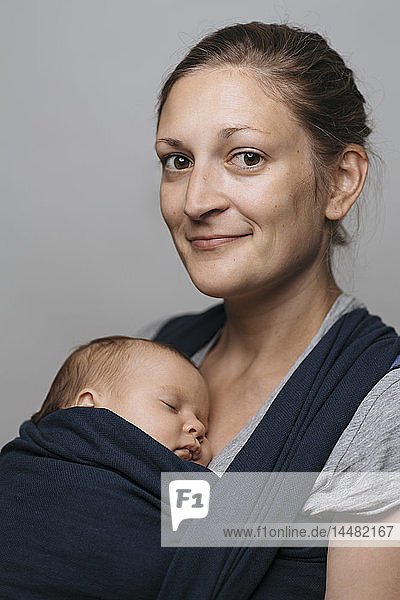Porträt einer lächelnden Mutter mit Baby im Babytragetuch