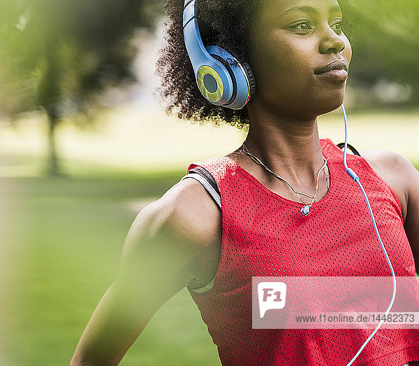 Sportliche junge Frau mit Kopfhörern im Park