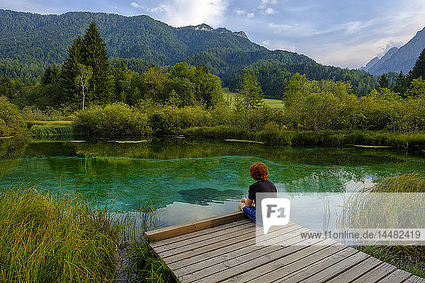 Slovenia  Gorenjska  near Ratece  Sava Dolinka  source  Lake Zelenci  young man sitting on jetty