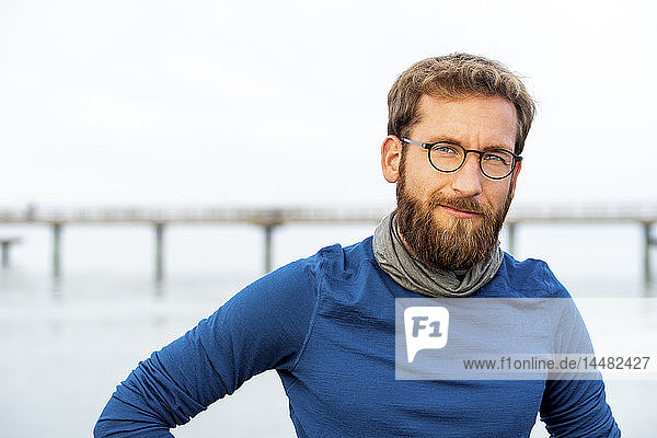 Deutschland  Rerik  Porträt eines bärtigen Mannes vor dem Meer mit einer Brille mit Metallgestell