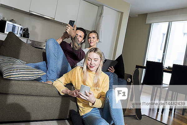 Friends sitting on couch in livingroom  using digital devices