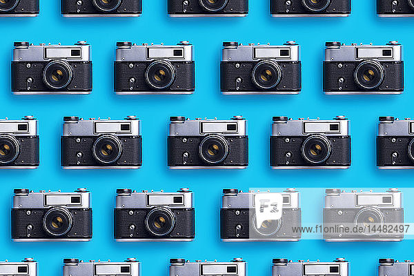 In einer Reihe angeordnete Fotokameras auf blauem Hintergrund