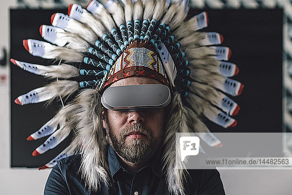 Man wearing Indian headdress and VR glasses in office
