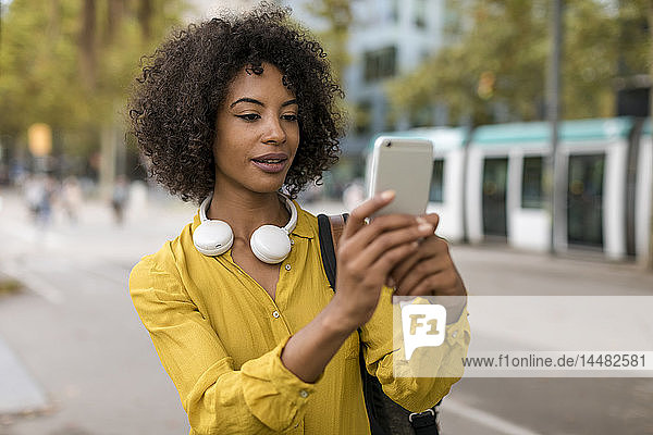 Porträt einer Frau mit Kopfhörern  die mit einem Smartphone Selbstgespräche führt
