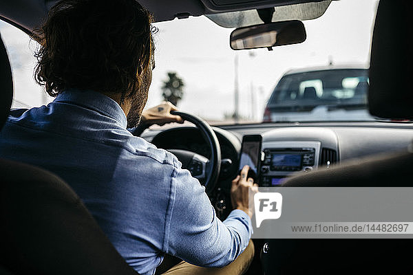 Businessman driving car using cell phone as navigation system