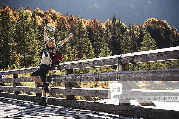 Österreich  Alpen  glückliche Frau auf einer Wanderung mit Karte auf einer Brücke