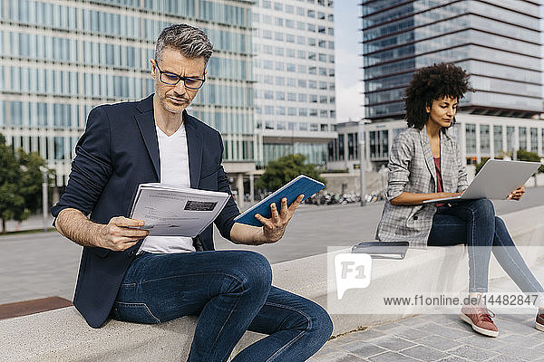 Businessman and businesswoman working outside office building