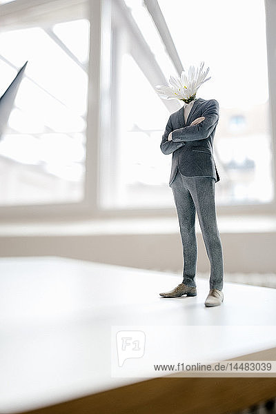 Geschäftsmann-Figur mit Blumenkopf auf Schreibtisch stehend