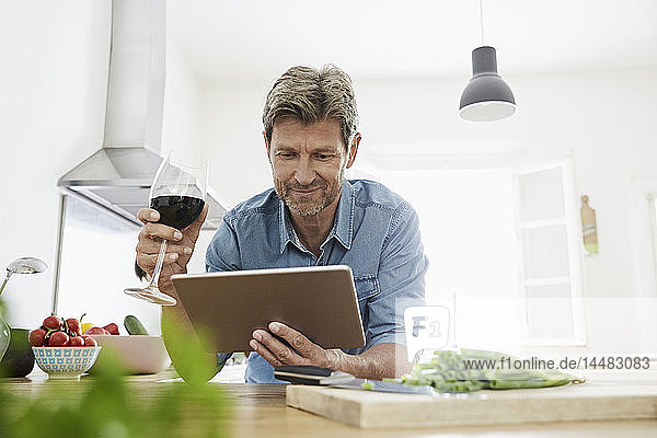 Reifer Mann in seiner Küche liest Rezept auf seinem digitalen Tablett