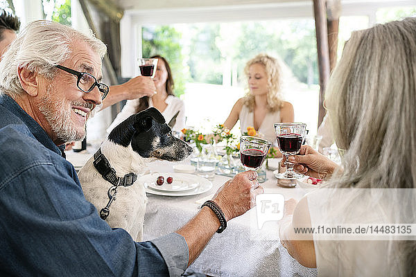 Älteres Ehepaar klimpert auf einer Familienfeier mit Weingläsern