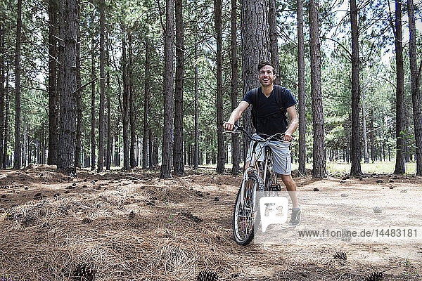 Young man cycling in pine forest