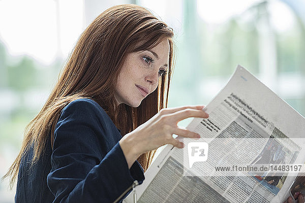 Geschäftsfrau liest Zeitung im Hotel