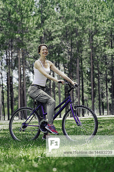 Frau auf Fahrrad im Wald sitzend