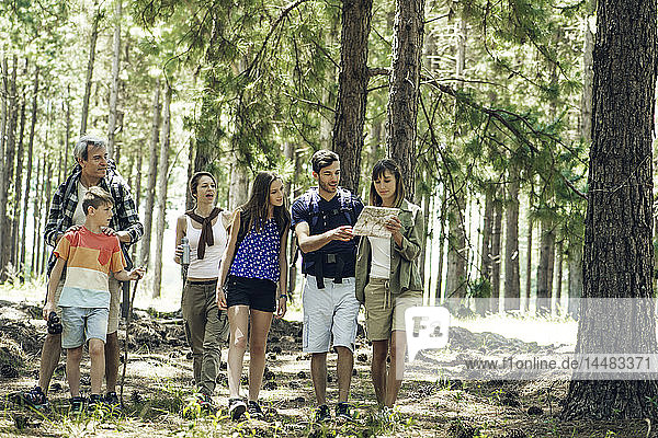 Familie  die im Wald stehend eine Karte liest