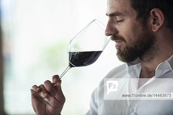 Close-up of mid adult man smelling red wine