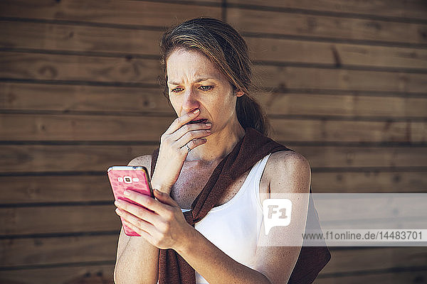 Seriöse reife Frau schaut auf Smartphone