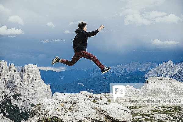 Unbekümmerter Junge springt über Felsen am Berg  Naturpark Drei Zinnen  Südtirol  Italien