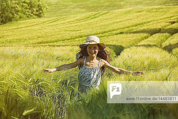 Porträt glückliches  sorgloses Mädchen  das auf einem sonnigen Feld läuft