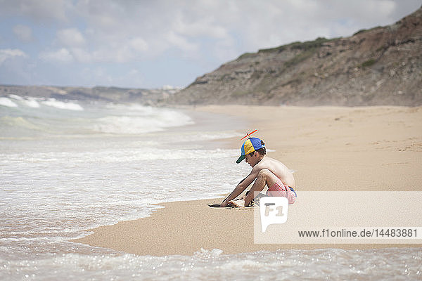 Boy playing in sand on sunny ocean beach  Lisboa  Lisbon  Portugal
