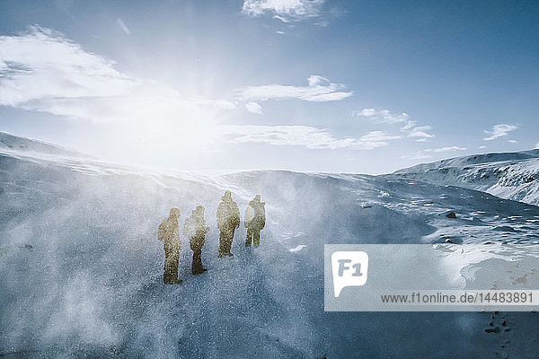 Spaziergänger in sonniger  windiger  schneebedeckter Landschaft  Reykjadalur  Island