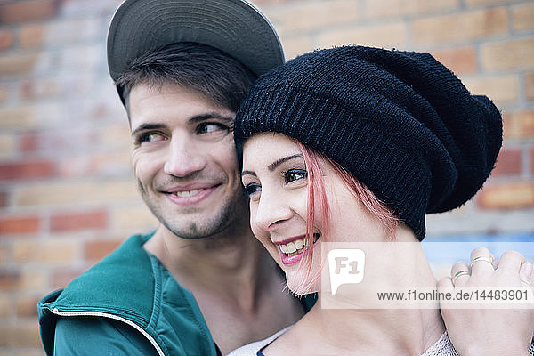 Lächelndes  zärtliches junges Paar schaut weg