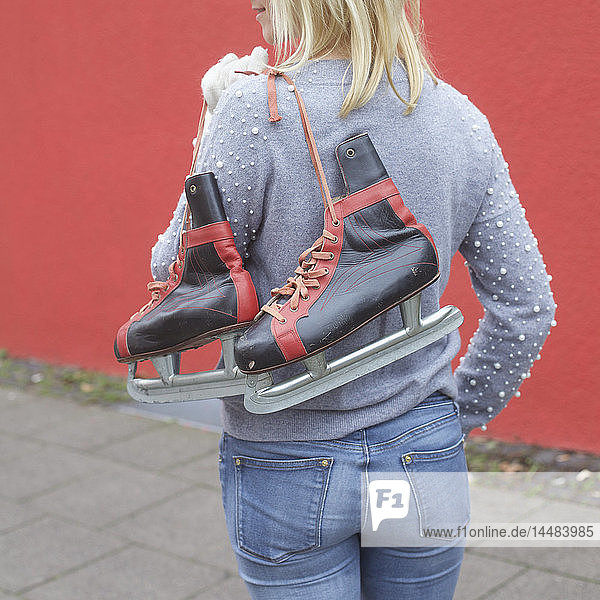 Woman carrying ice skates over shoulder