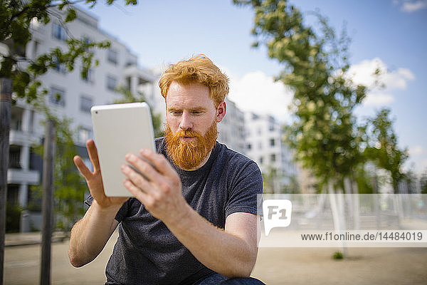 Man with beard using digital tablet in city