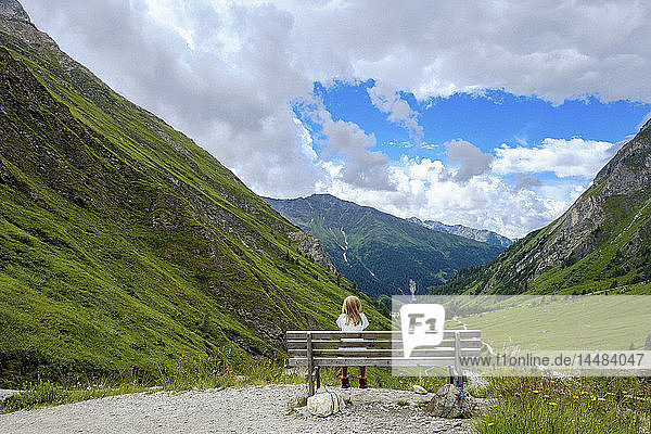 Mädchen auf einer Bank sitzend mit Blick auf eine malerische Berglandschaft  Innergschloess  Tirol  Österreich