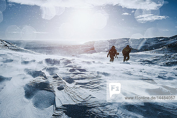 Vater und Sohn wandern an einem sonnigen  schneebedeckten Berg entlang  Reykjadalur  Island