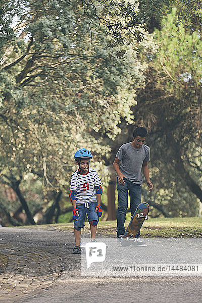 Brothers skateboarding in park