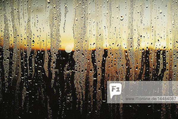 Regentropfen und Kondenswasser am Fenster mit Blick auf den Sonnenuntergang